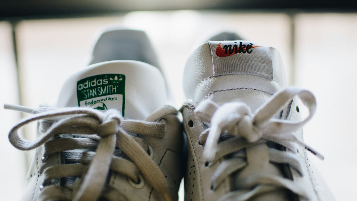 An adidas Stan Smith and a Nike sneaker standing side by side