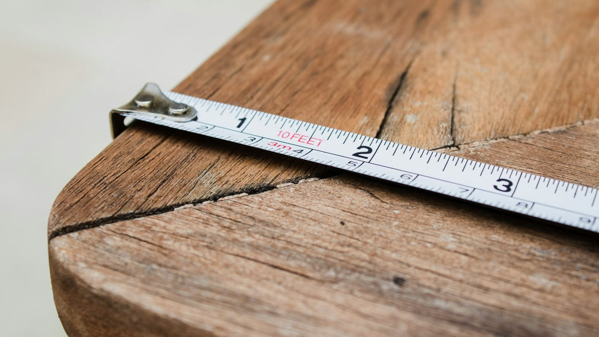 A tape measure unrolled across a wooden table
