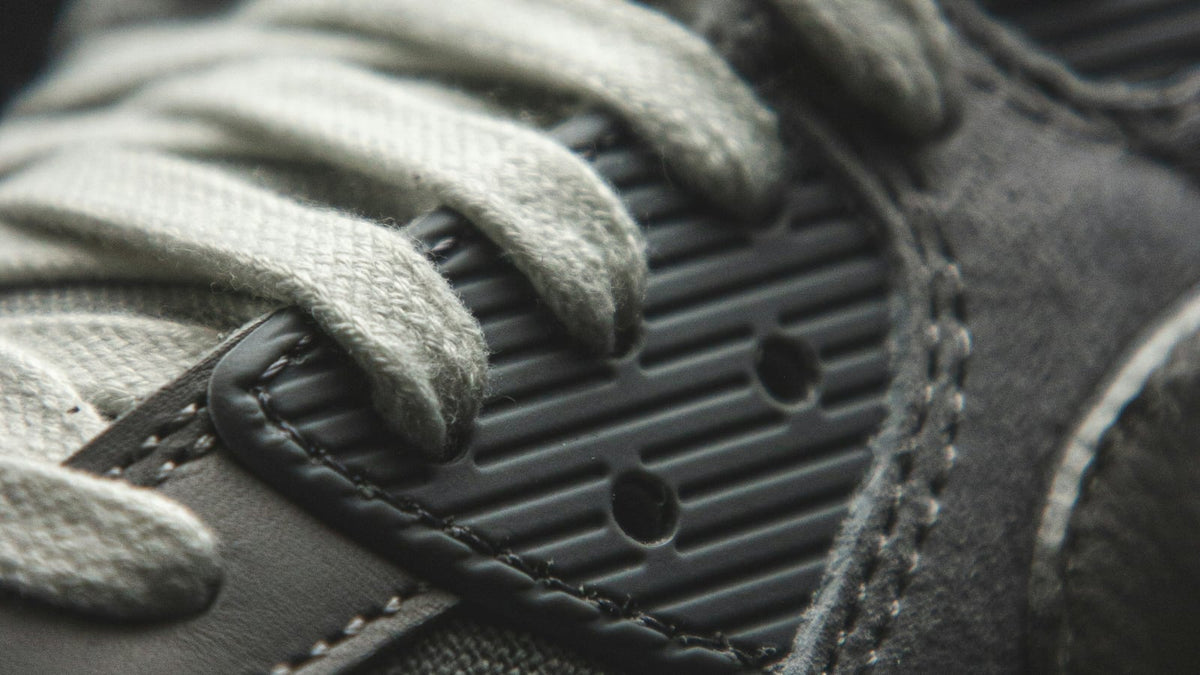 Macro close-up of a sneaker showing lace weave, panel stitching and the perforated midsole