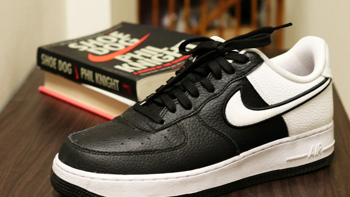 A black and white Nike Air Force 1 resting on a wooden surface