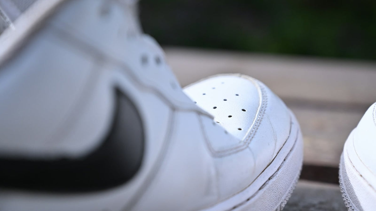 Close-up of the toe box and side panel of a white leather sneaker