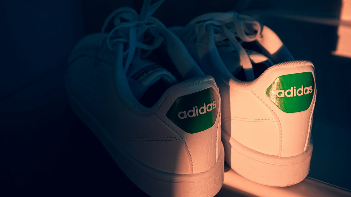 A pair of white adidas Stan Smiths showing their green heel tabs