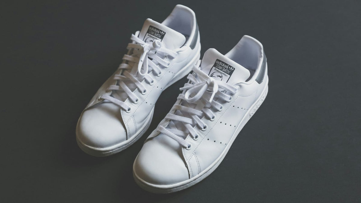 A pair of white adidas court sneakers photographed from above