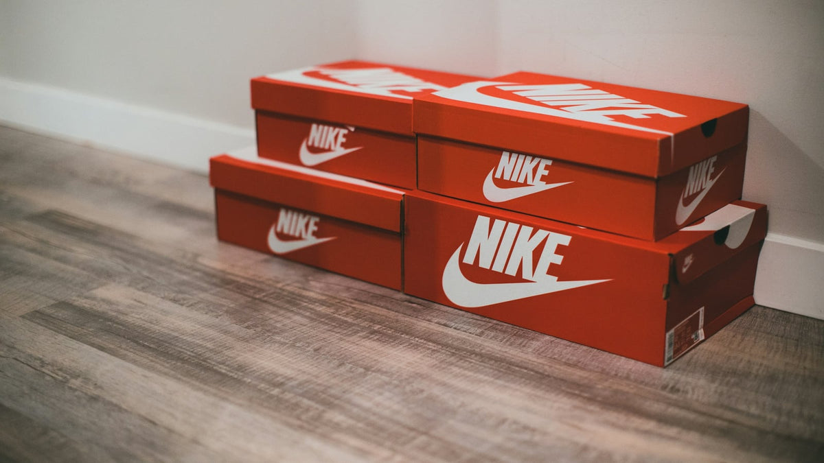 Stacked red Nike shoe boxes on a wooden floor
